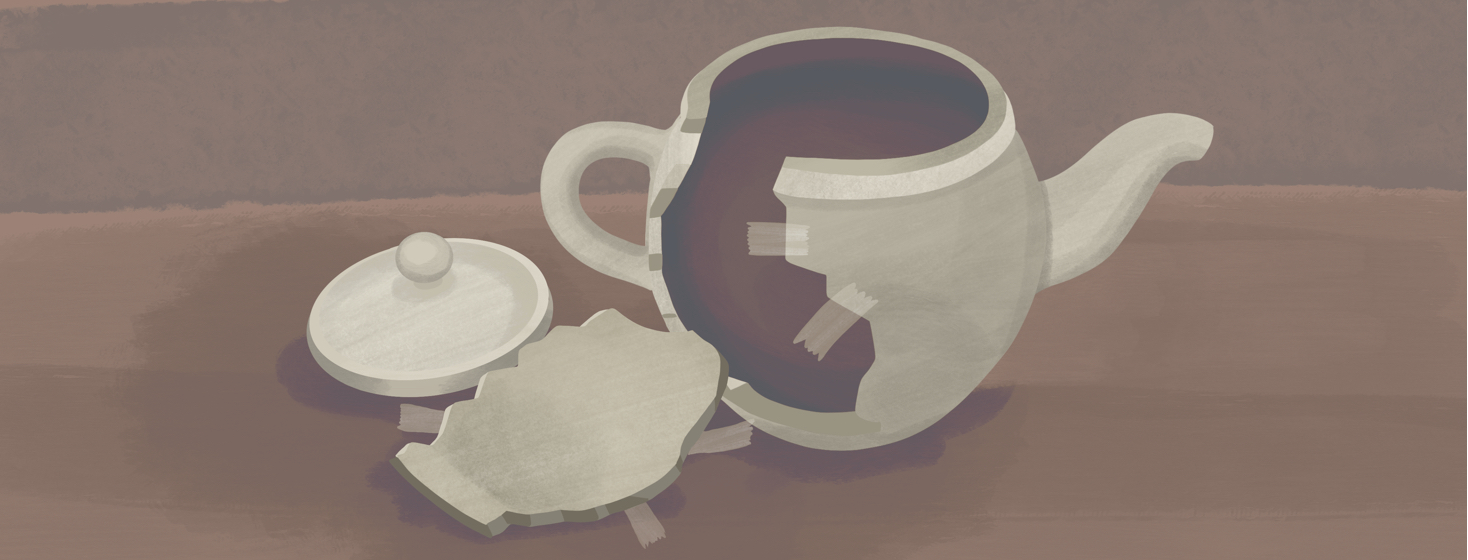 A broken teapot has a piece that has fallen onto the table next to it, while pieces of tape remain on both parts where countless attempts to fix it have taken place.