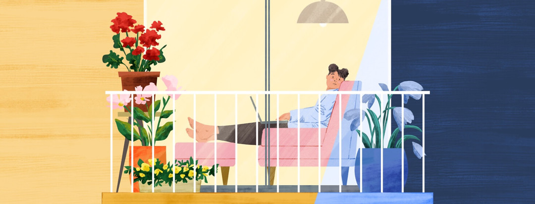 A woman sitting inside on a couch, wistfully looking out glass doors to her outdoor balcony, which is filled with potted plants